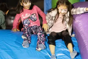 2-girls-slide-on-bounce-house-AMS-Event-1